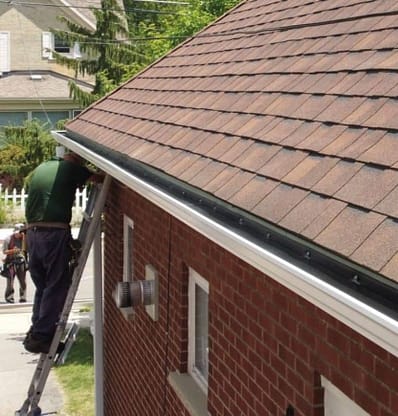 A service technician performing a gutter guard installation on a home in Southwestern Ontario