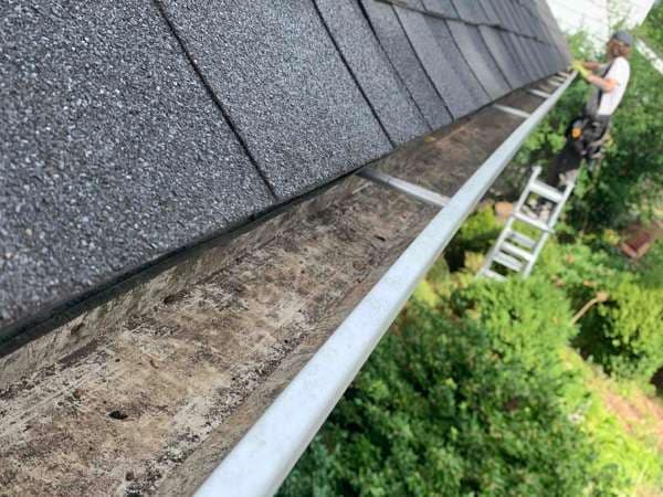 A Home Service Solutions technician cleaning a gutter
